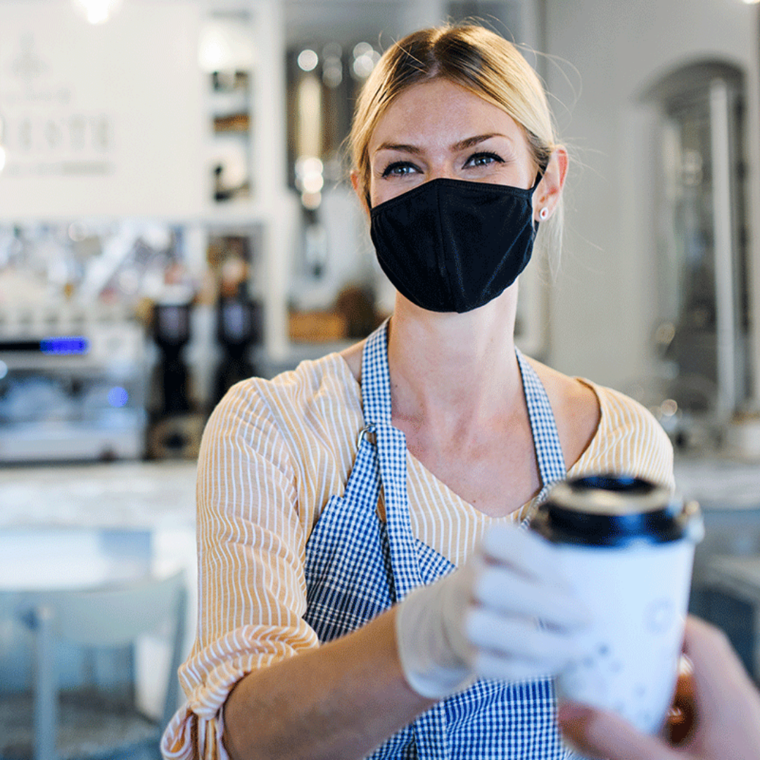 Photo of person in mask serving coffee
